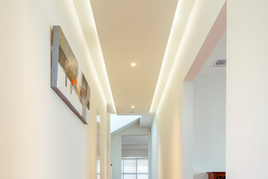 На фото: коридор в стиле модернизм с белыми стенами и светлым паркетным полом с