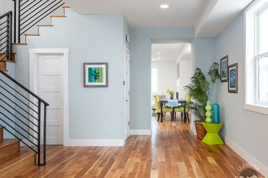 Modelo de recibidores y pasillos minimalistas grandes con paredes azules y suelo de madera en tonos medios