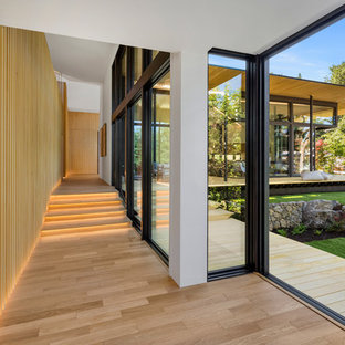 Idée de décoration pour un couloir design avec un sol en bois clair et un sol beige.