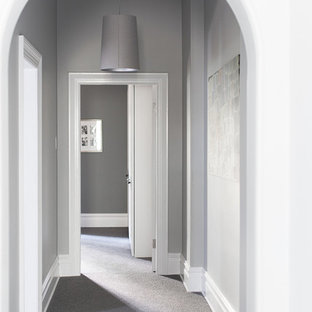 Aménagement d'un grand couloir victorien avec un mur gris, moquette et un sol gris.