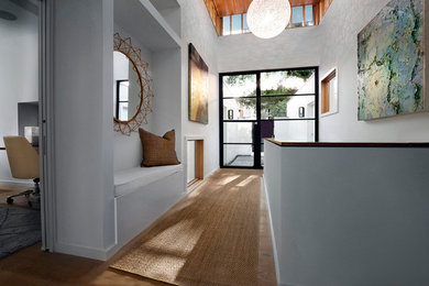 Example of a large minimalist medium tone wood floor hallway design in Austin with white walls