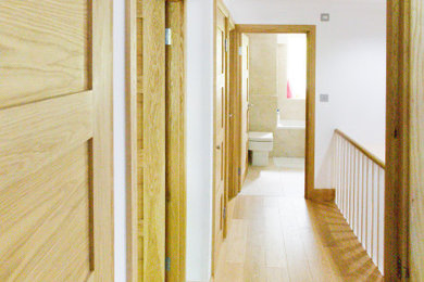 Imagen de recibidores y pasillos minimalistas de tamaño medio con paredes blancas, suelo de madera clara y suelo amarillo