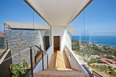 Aménagement d'un couloir contemporain avec un mur blanc et un sol en bois brun.