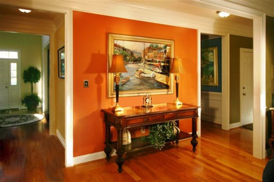 Inspiration for a mid-sized timeless orange floor and medium tone wood floor hallway remodel in Richmond with orange walls