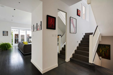 Großer Moderner Flur mit weißer Wandfarbe, dunklem Holzboden und braunem Boden in London
