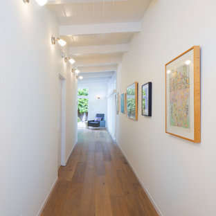 Aménagement d'un couloir rétro de taille moyenne avec un mur blanc et un sol en bois brun.