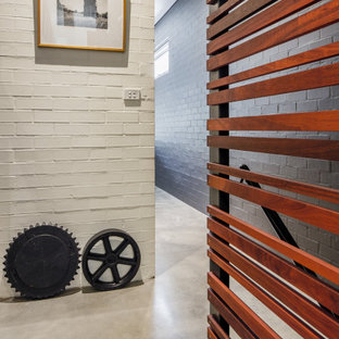 Modern inredning av en mellanstor hall, med vita väggar, betonggolv och grått golv