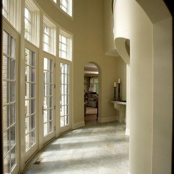 Curved Two Story Hallway with French Doors and Limestone Floors