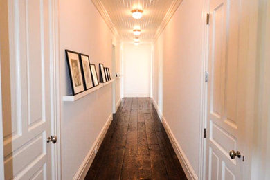 Large elegant dark wood floor and brown floor hallway photo in New York with white walls