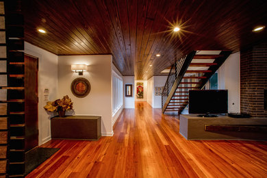 Example of a large trendy medium tone wood floor and brown floor hallway design in New Orleans with beige walls