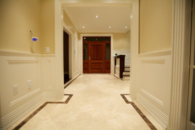 Example of a large limestone floor and beige floor hallway design in Toronto with yellow walls