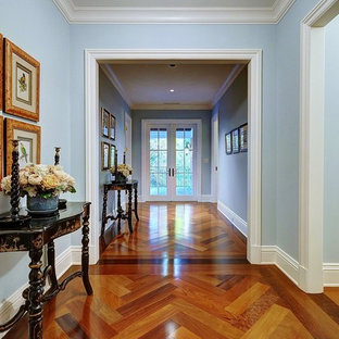 Exemple d'un couloir chic avec un mur bleu et un sol en bois brun.