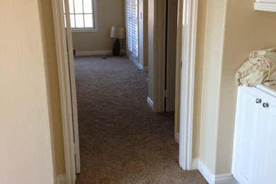 Inspiration for a mid-sized coastal carpeted hallway remodel in Orange County with beige walls