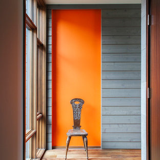 Cette image montre un couloir design avec un mur orange et un sol en bois brun.