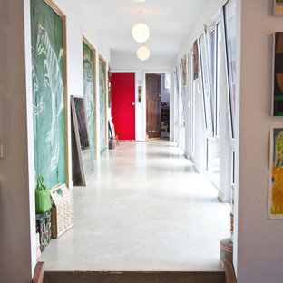 Idées déco pour un couloir éclectique de taille moyenne avec un mur blanc, béton au sol et un sol blanc.