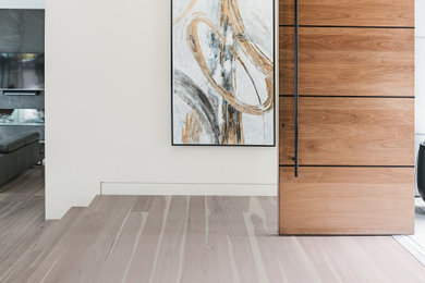 Example of a large trendy light wood floor and gray floor hallway design in Vancouver with white walls