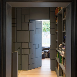 Inspiration pour un couloir design avec un mur gris, un sol en bois clair et du lambris.