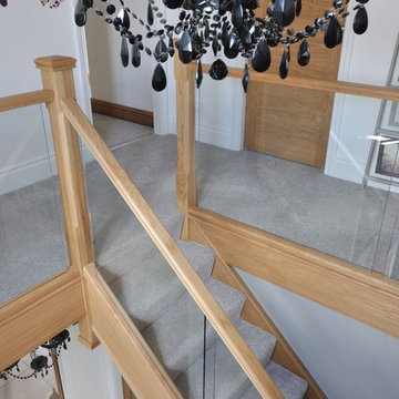 Modern staircase with a mix of glass and natural oak and carpeted treads
