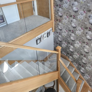 Modern staircase with a mix of glass and natural oak and carpeted treads
