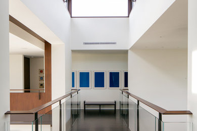 Стильный дизайн: большой коридор в современном стиле с белыми стенами и темным паркетным полом - последний тренд