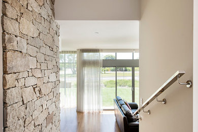Ejemplo de recibidores y pasillos actuales con paredes beige y suelo de madera en tonos medios
