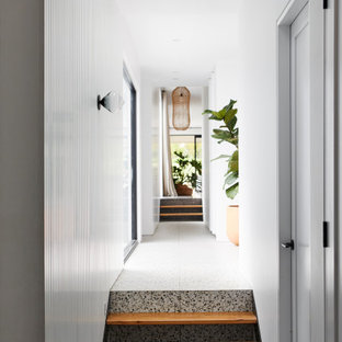 Idée de décoration pour un grand couloir design avec un mur blanc, béton au sol, un sol noir et du lambris.