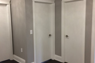 Cette photo montre un couloir chic de taille moyenne avec un mur gris, parquet peint et un sol marron.