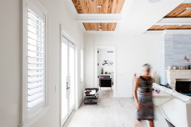 Hallway - large tropical light wood floor hallway idea in Miami with white walls