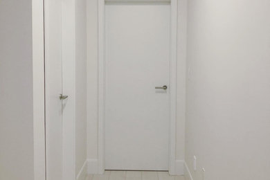 Imagen de recibidores y pasillos modernos de tamaño medio con paredes blancas, suelo vinílico y suelo blanco