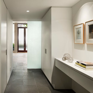 Exempel på en modern hall, med vita väggar och grått golv
