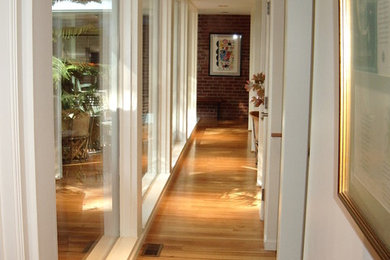 Foto de recibidores y pasillos modernos con paredes blancas y suelo de madera en tonos medios