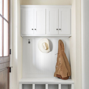 Inspiration pour un couloir rustique de taille moyenne avec un mur beige, béton au sol, un sol marron, un plafond voûté et boiseries.