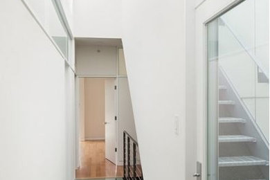 Ejemplo de recibidores y pasillos modernos con paredes blancas, suelo de madera en tonos medios y suelo marrón