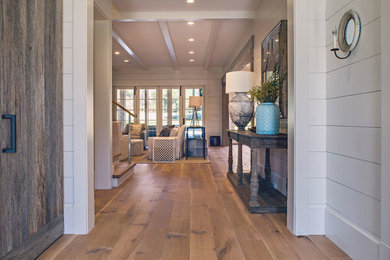 Example of a farmhouse medium tone wood floor hallway design in Atlanta with white walls