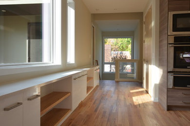 Diseño de recibidores y pasillos modernos con paredes beige y suelo de madera en tonos medios