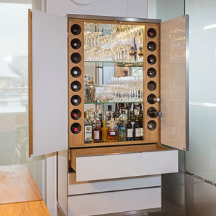 Imagen de bar en casa actual, pequeño, con armarios con paneles lisos, puertas de armario blancas, suelo de madera en tonos medios, encimera de madera y salpicadero con efecto espejo
