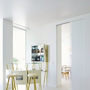 Imagen de bar en casa con barra de bar lineal, actual, extra grande, con armarios tipo mueble, puertas de armario blancas, encimera de vidrio, salpicadero con efecto espejo, suelo de cemento y suelo gris