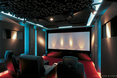 This is an example of a large urban home cinema in Dortmund with carpet, a projector screen and red floors.