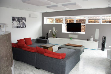 Modelo de cine en casa abierto actual grande con paredes grises, suelo de mármol, pared multimedia y suelo blanco