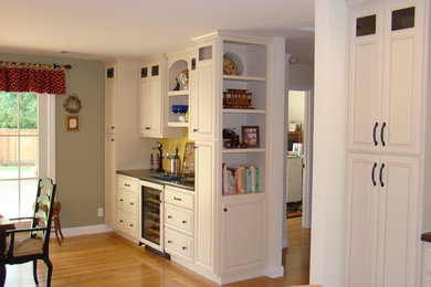 Example of a mid-sized classic single-wall light wood floor and brown floor wet bar design in San Francisco with raised-panel cabinets, white cabinets, quartz countertops and black countertops