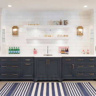 Foto de bar en casa con fregadero lineal, marinero, con fregadero bajoencimera, armarios estilo shaker, puertas de armario azules, salpicadero blanco, salpicadero de madera, suelo gris, encimeras blancas y suelo de cemento