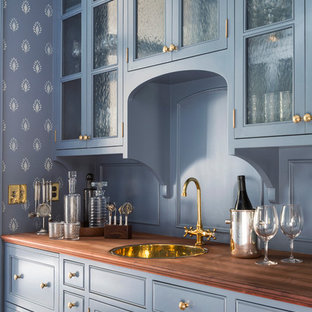 Immagine di un angolo bar con lavandino classico di medie dimensioni con lavello da incasso, ante di vetro, ante blu, top in legno, paraspruzzi blu e top marrone