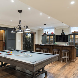Modelo de bar en casa con barra de bar marinero con armarios tipo vitrina, puertas de armario grises, suelo de madera oscura y suelo marrón