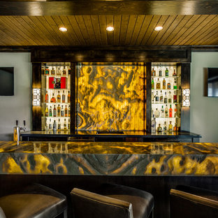 Cette photo montre un très grand bar de salon tendance en U avec des tabourets, un évier encastré, un placard sans porte, des portes de placard en bois sombre, un plan de travail en onyx, une crédence jaune, une crédence en dalle de pierre et un sol en bois foncé.