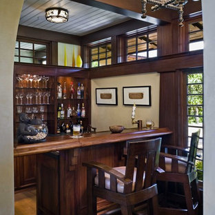 Immagine di un bancone bar tropicale di medie dimensioni con parquet scuro, ante in legno bruno, top in legno, top marrone e nessun'anta