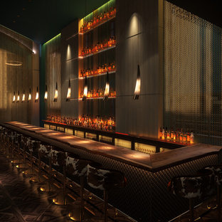Idée de décoration pour un très grand bar de salon bohème en L avec des tabourets, un plan de travail en bois et un sol en bois foncé.