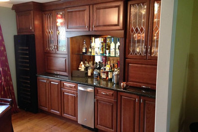 Cette image montre un bar de salon traditionnel en bois brun de taille moyenne avec un placard à porte vitrée et un plan de travail en granite.