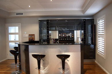 Exemple d'un bar de salon moderne en U de taille moyenne avec un placard à porte plane, des portes de placard noires, un plan de travail en granite, des tabourets et une crédence noire.