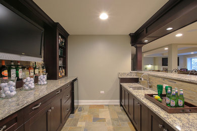Seated home bar - large traditional galley slate floor seated home bar idea in Chicago with an undermount sink, shaker cabinets, dark wood cabinets, granite countertops, beige backsplash and stone tile backsplash