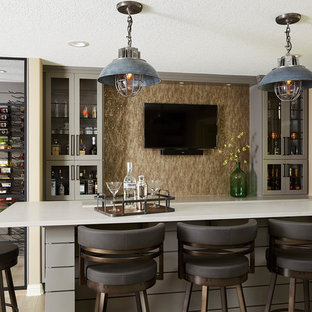 Idee per un bancone bar tradizionale di medie dimensioni con ante grigie, top in quarzite, parquet chiaro, ante di vetro, paraspruzzi beige e pavimento beige